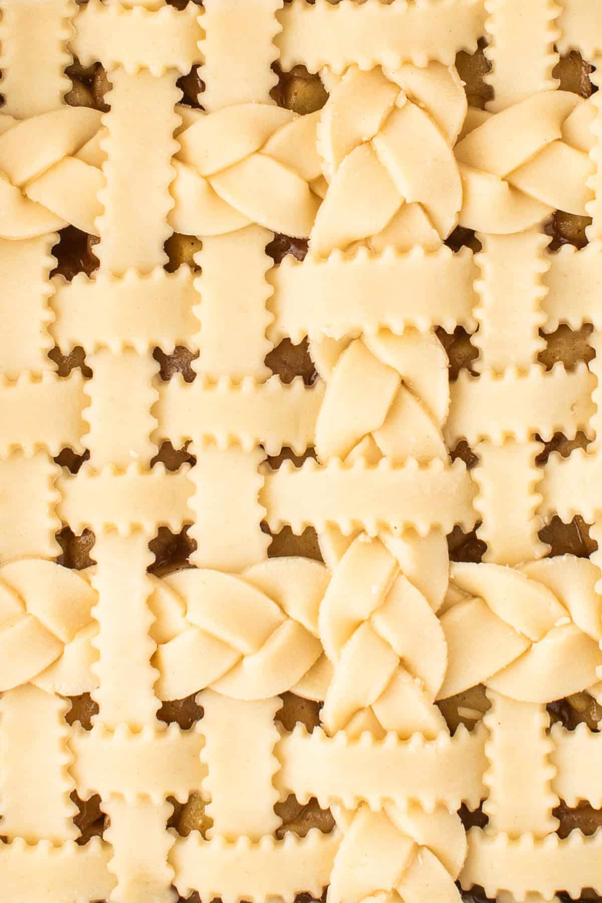 Unbaked pie with a lattice crust, featuring crimped and braided pastry strips in a decorative pattern—perfect for transforming into delightful Apple Pie Bars.