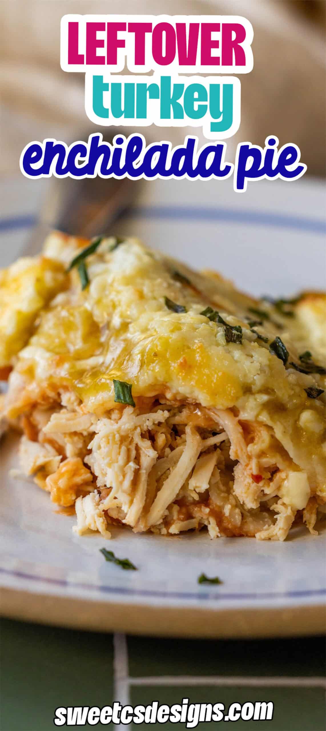 A slice of leftover turkey enchilada pie with melted cheese sits on a white plate, garnished with fresh herbs.