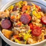 A bowl filled with bread pieces, sliced pepperoni, chopped peppers, and herbs, mixed together in a savory stuffing dish.