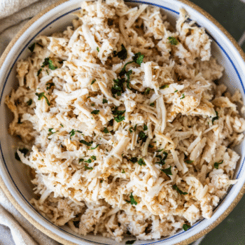 A bowl filled with shredded turkey breast, garnished with chopped herbs, perfect for showcasing slow cooker flavors.
