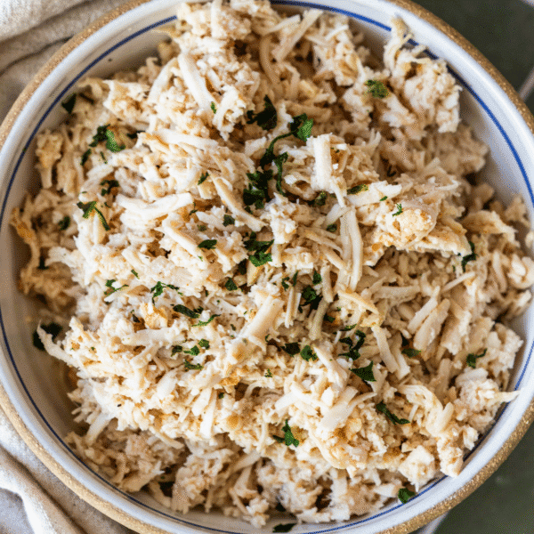 A bowl filled with shredded turkey breast, garnished with chopped herbs, perfect for showcasing slow cooker flavors.