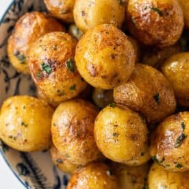 A bowl filled with roasted butter potatoes seasoned with herbs and spices.
