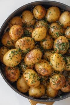 A pan filled with roasted baby potatoes garnished with chopped herbs, perfect as a delicious side dish for Baked Pork Chops.