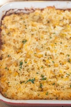 A Cheesy Corn Rice Casserole featuring a golden-brown rice and corn mixture, topped with chopped green herbs, makes for a comforting baked casserole dish.