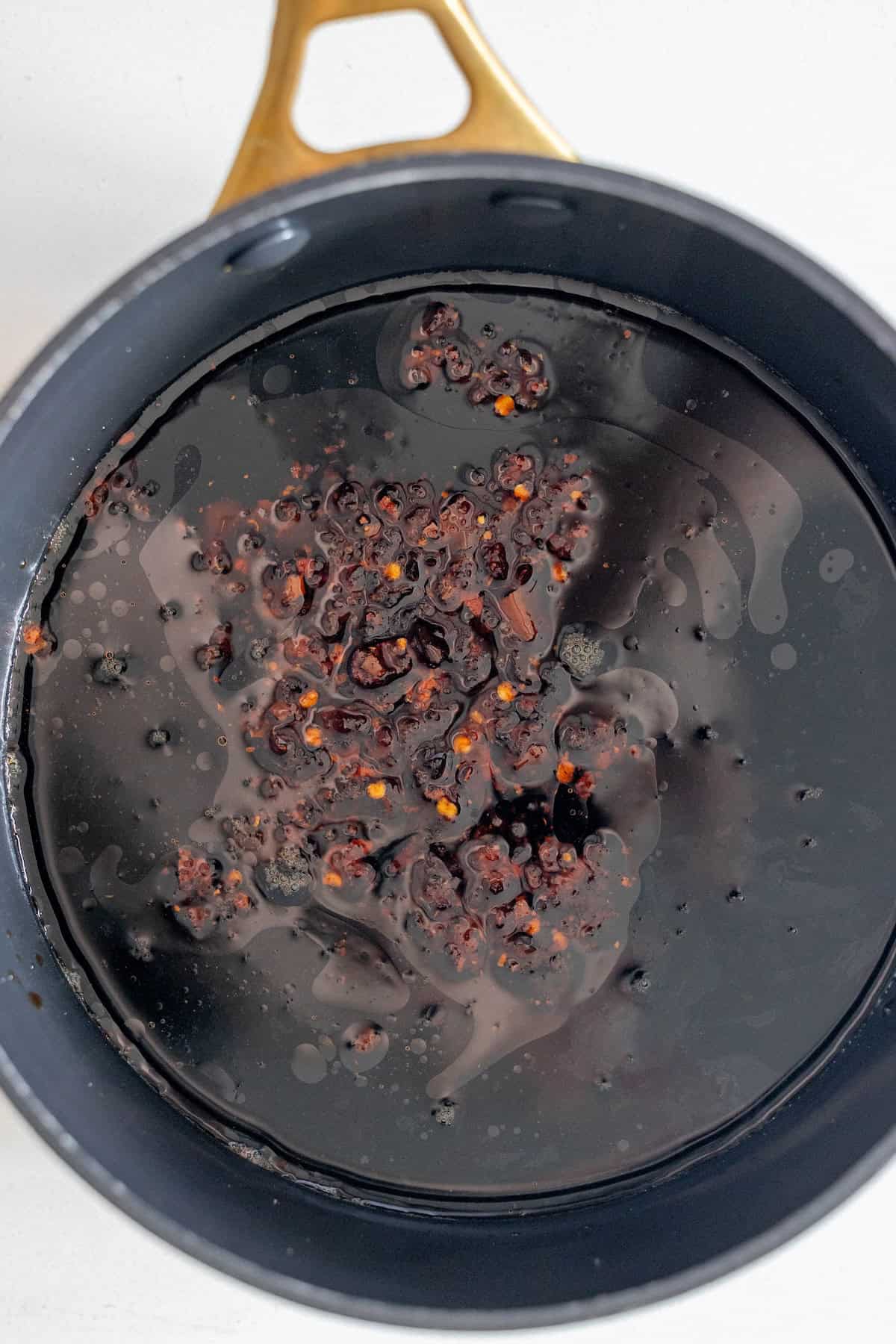 A pot filled with a dark liquid and chili flakes, viewed from above&mdash;perfect for making easy Mongolian Beef that tastes just like your favorite takeout.