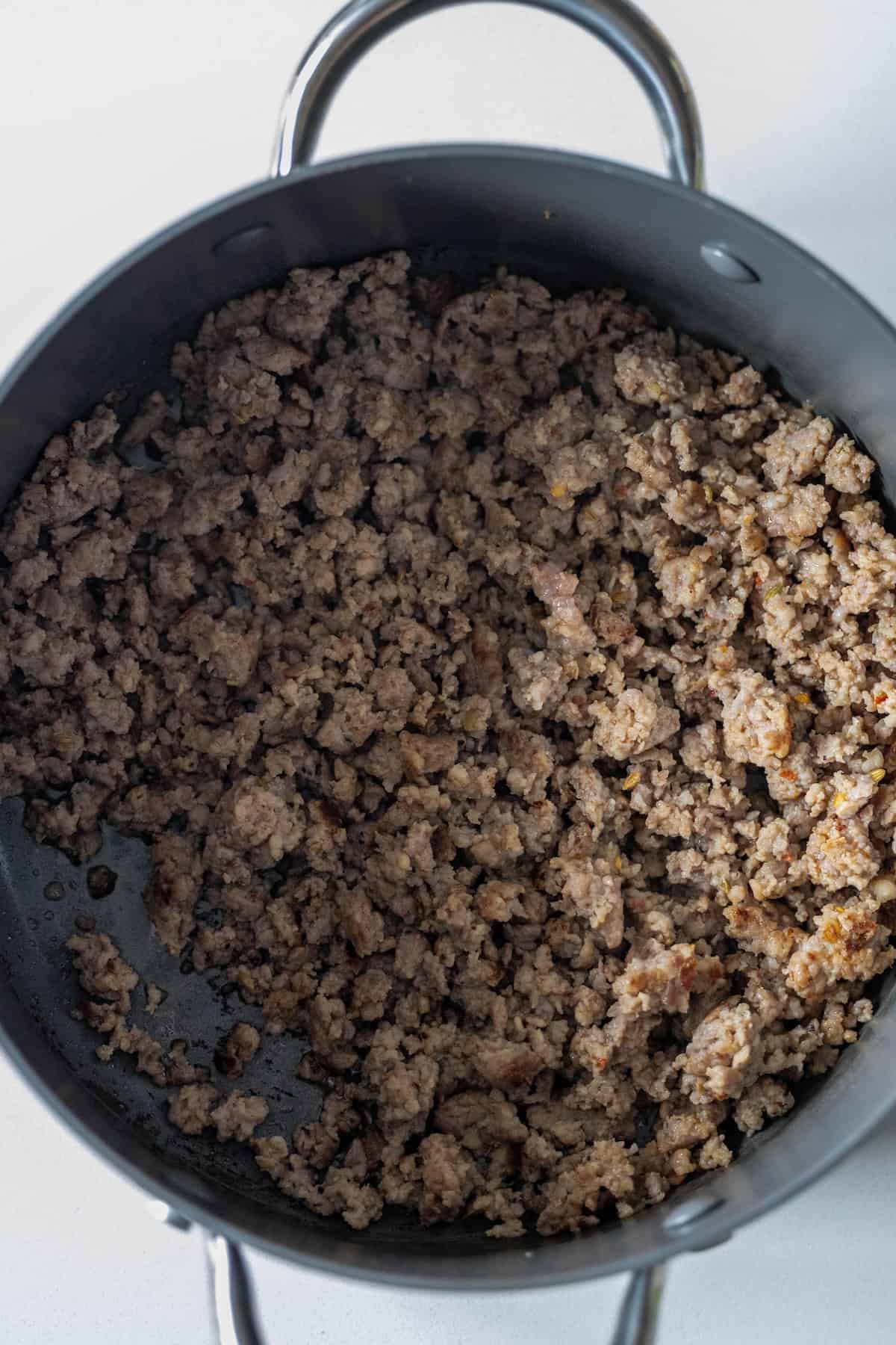 Cooked ground beef in a black pot on a light-colored countertop, perfect for starting a delicious Ground Beef Casserole.