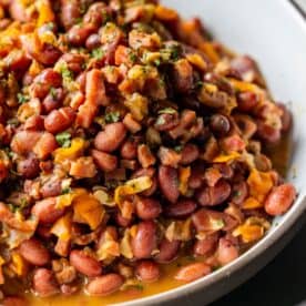 A close-up of a bowl filled with stewed kidney beans, diced carrots, onions, and herbs in a savory sauce&mdash;an old-fashioned ham and bean recipe perfect for cozy evenings.