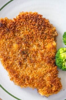A classic Pork Schnitzel, breaded and fried to golden perfection, is served on a plate with a side of steamed broccoli—a delicious schnitzel recipe for any occasion.