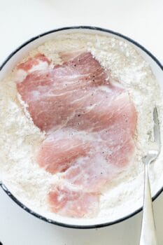 A bowl of food with a spoon, featuring a delicious Pork Schnitzel recipe.