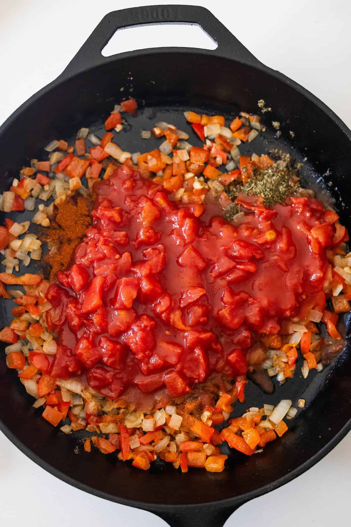Chopped onions and red bell peppers sautéed in a black skillet, topped with canned diced tomatoes and spices—this is an Easy Shakshuka perfect for a flavorful breakfast or brunch.