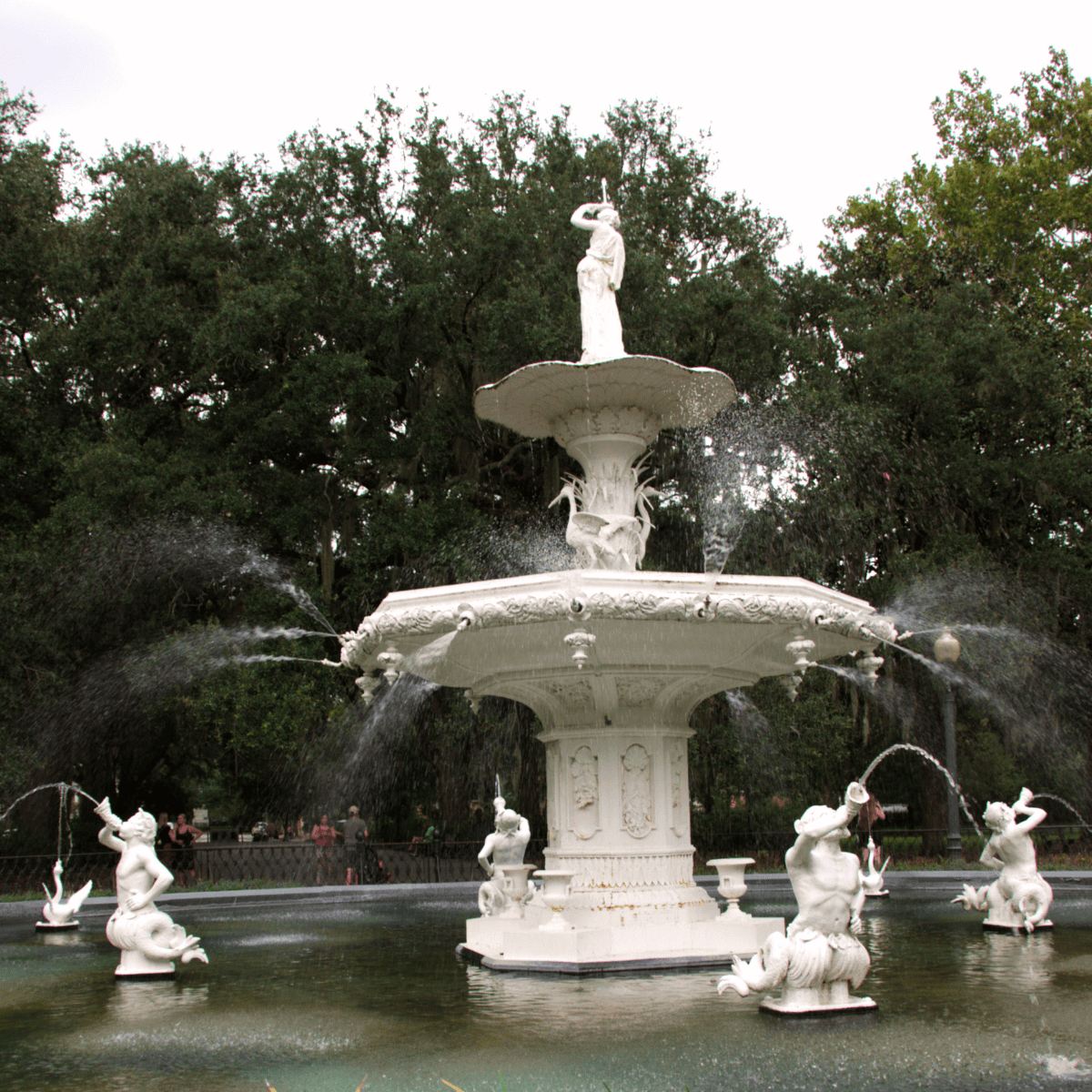 Large ornate fountain with multiple tiers and statues, water spraying from various points, surrounded by greenery and trees&mdash;a must-see highlight in any savannah travel guide.