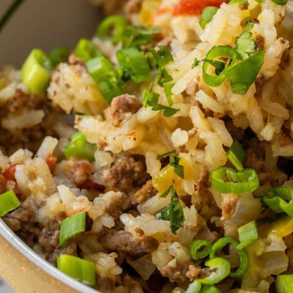 Close-up of a Baked Dirty Rice casserole with ground meat, topped with chopped green onions and herbs.