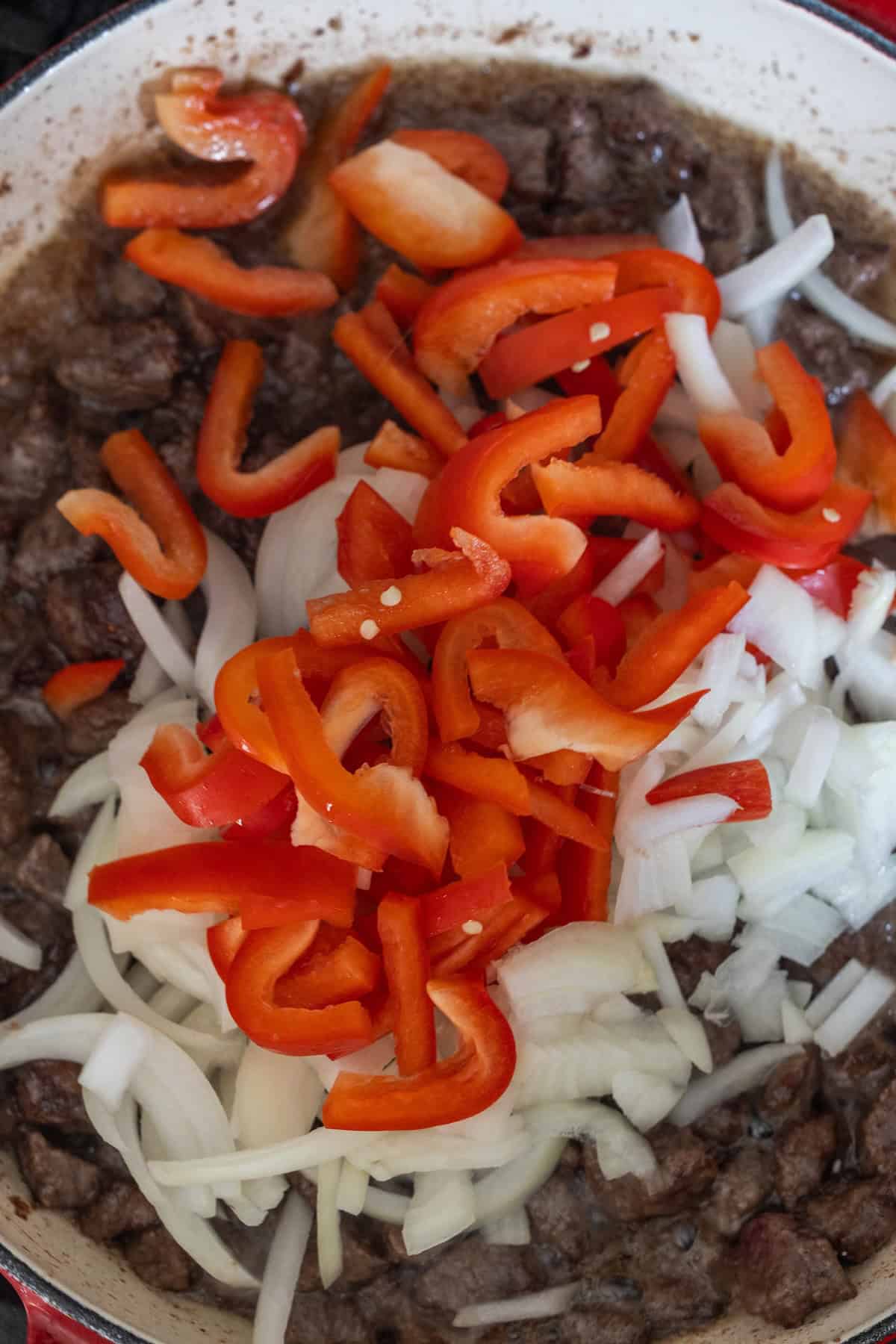 A bowl of food with chopped onions and peppers, featuring a savory pepper and beef stir fry that's sure to impress.