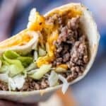 A close-up of a taco filled with ground beef, shredded lettuce, and melted cheddar cheese in a flour tortilla, reminiscent of Easy Cheeseburger Wraps for a delicious twist on the classic taco.
