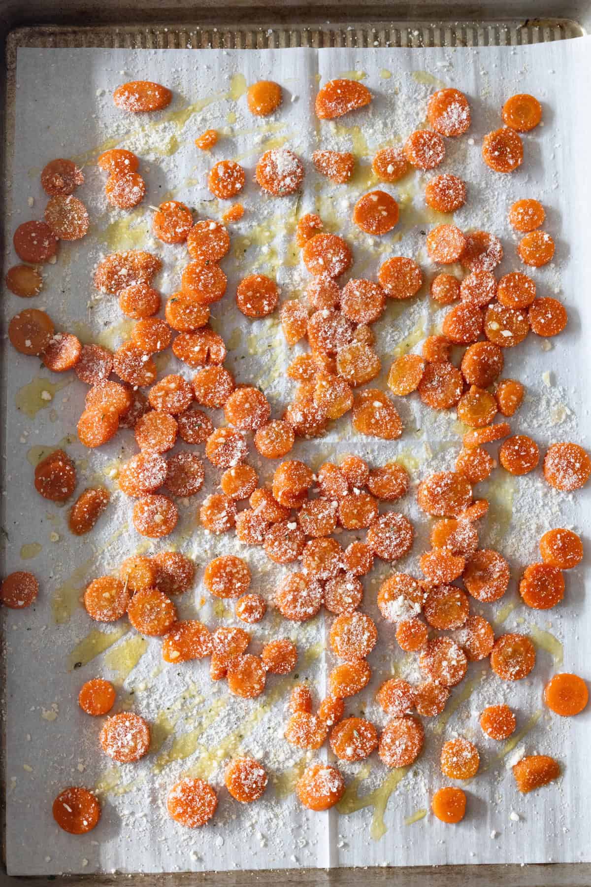 Sliced carrots coated with oil, sprinkled with garlic parmesan and seasonings, then roasted on a parchment-lined baking sheet.
