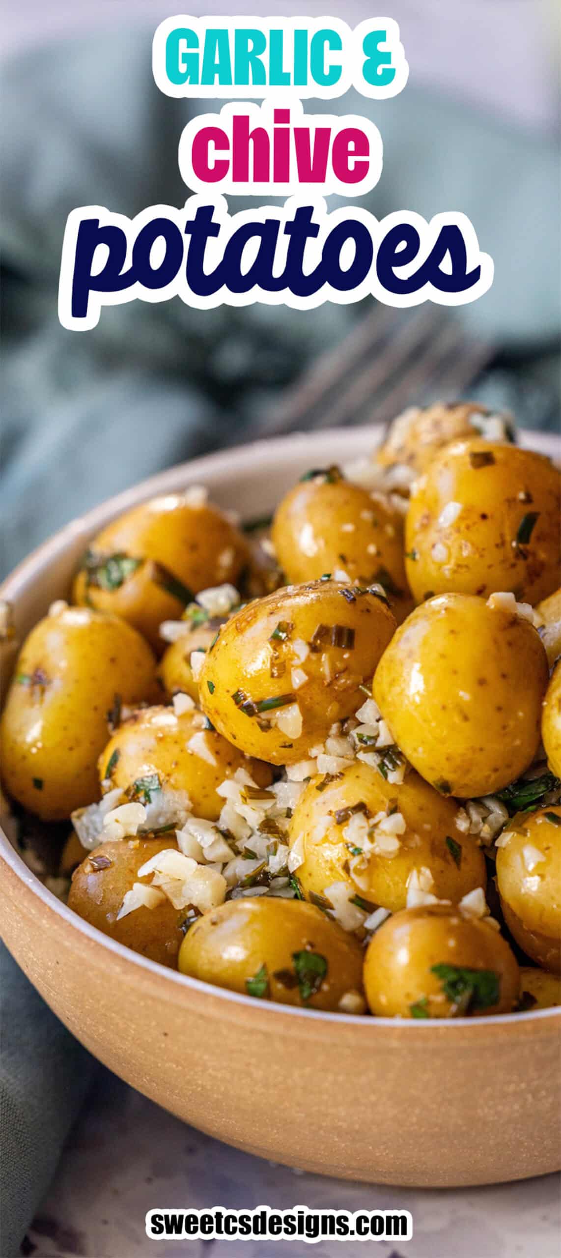 A bowl of cooked garlic and chive potatoes is garnished with chopped garlic and fresh chives.