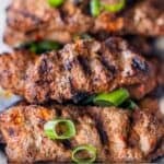 Armenian kebabs of spiced meat with visible grill marks, garnished with chopped green onions.