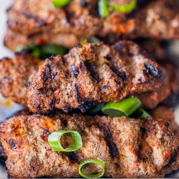 Armenian kebabs of spiced meat with visible grill marks, garnished with chopped green onions.