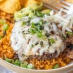 Enjoy our Burger Bowls: a hamburger patty topped with melted cheese, chopped green onions, and zesty green chile served over seasoned rice, with chips, guacamole, and shredded cheese on the side.