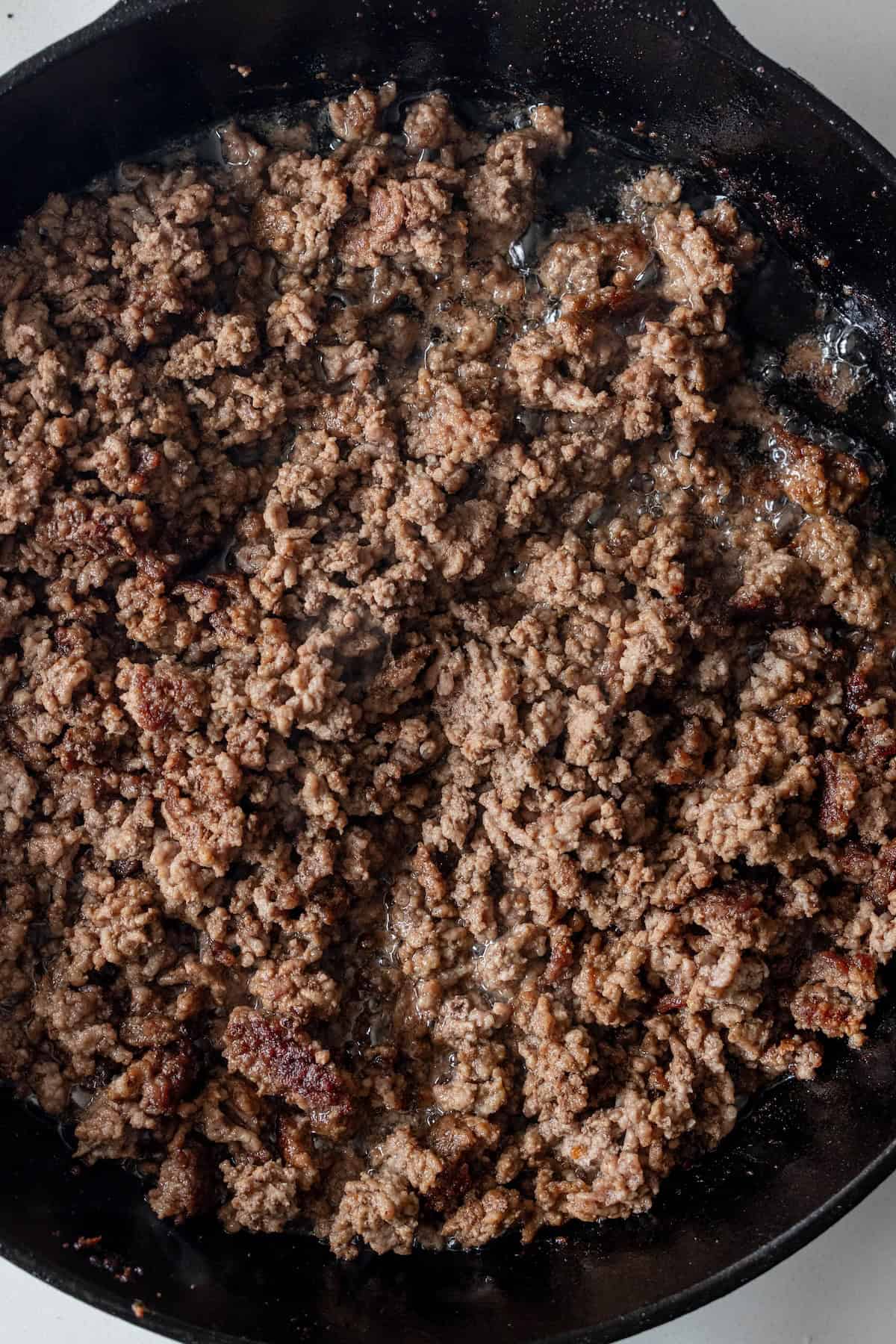 Ground beef for a potato and beef bake browning in a cast iron skillet.