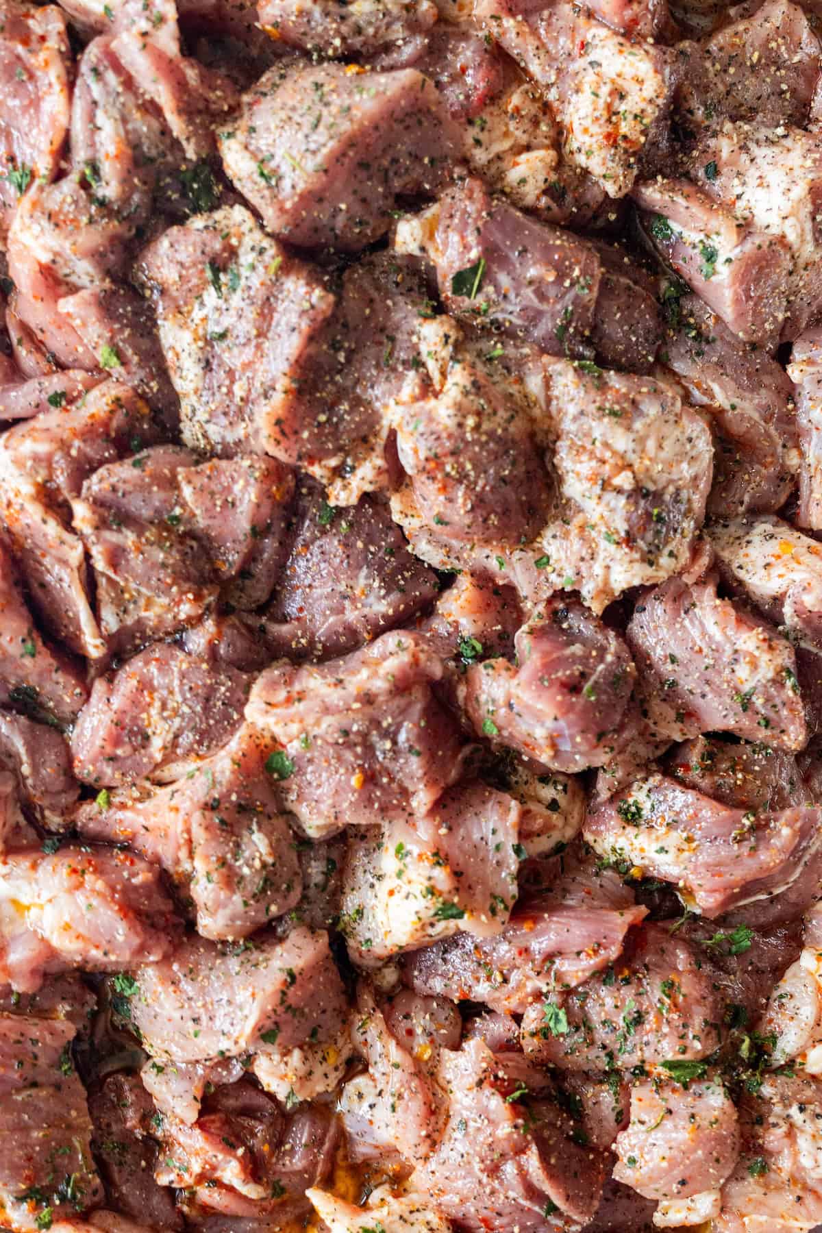 Raw, cubed onion-marinated pork seasoned with herbs and black pepper.