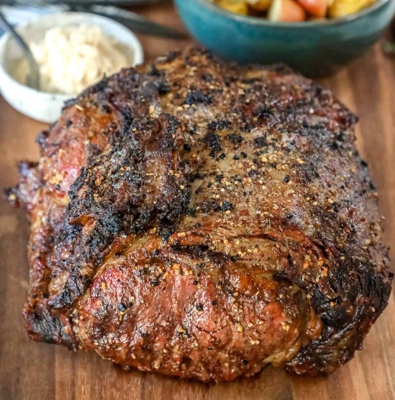 The Best Ribeye Roast Recipe with potatoes served on a cutting board.